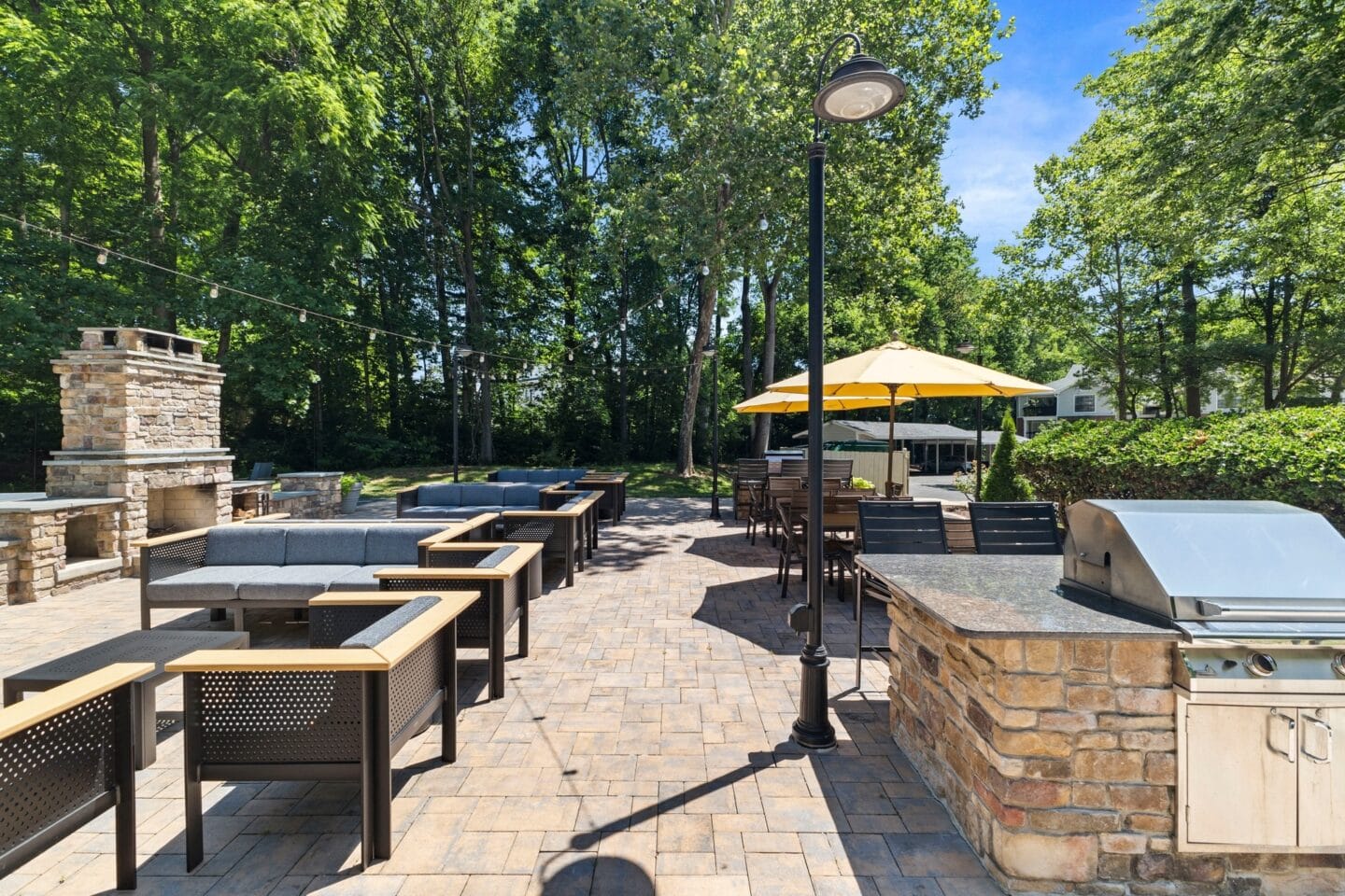 a patio with tables and umbrellas and a barbecue grill