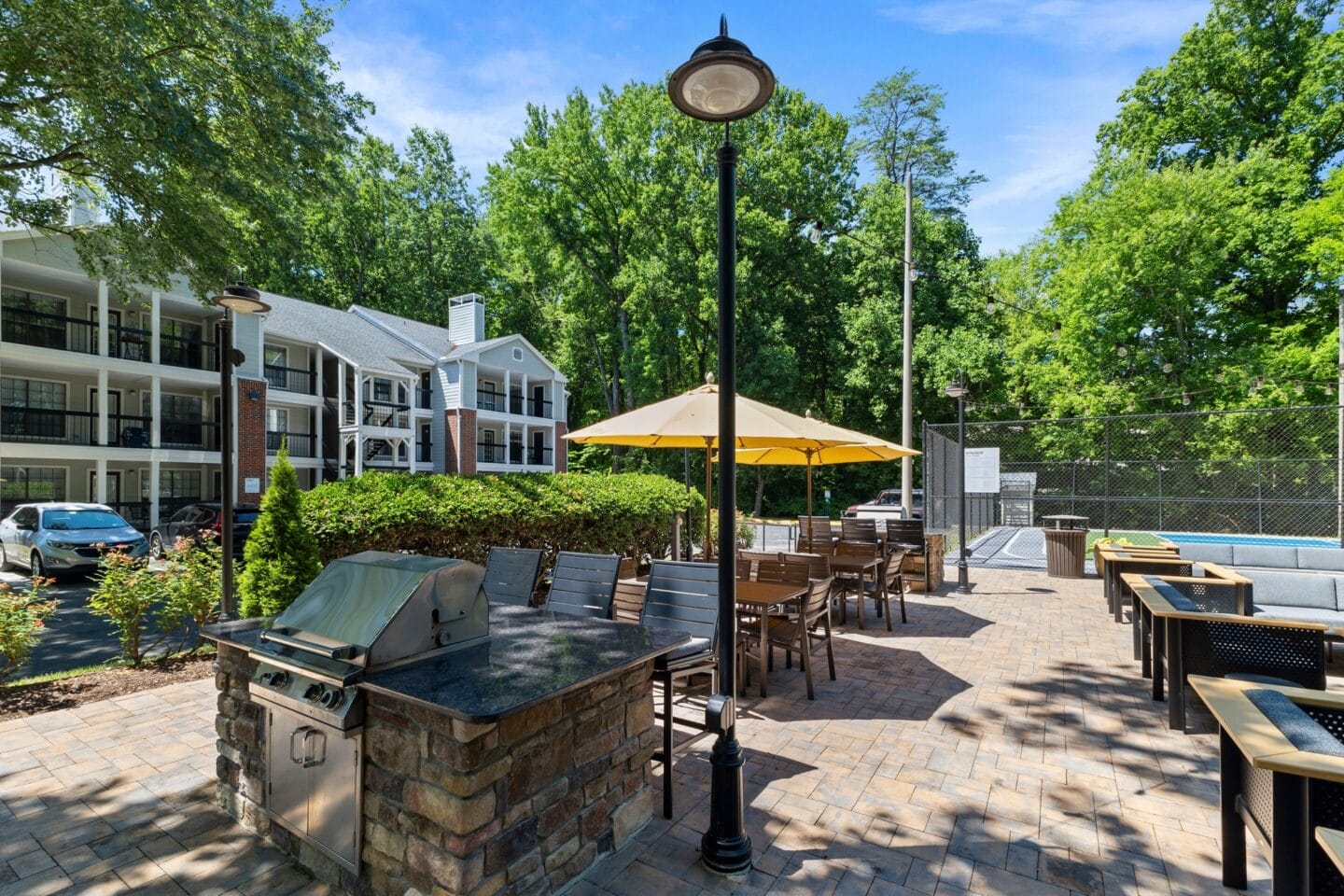 a patio with a grill and tables with umbrellas