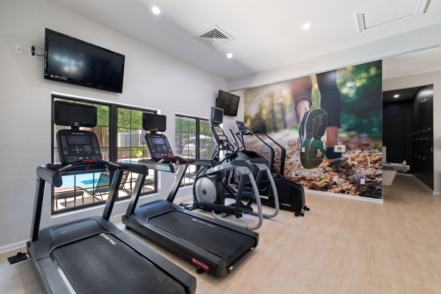 the gym is equipped with cardio equipment and a flat screen tv