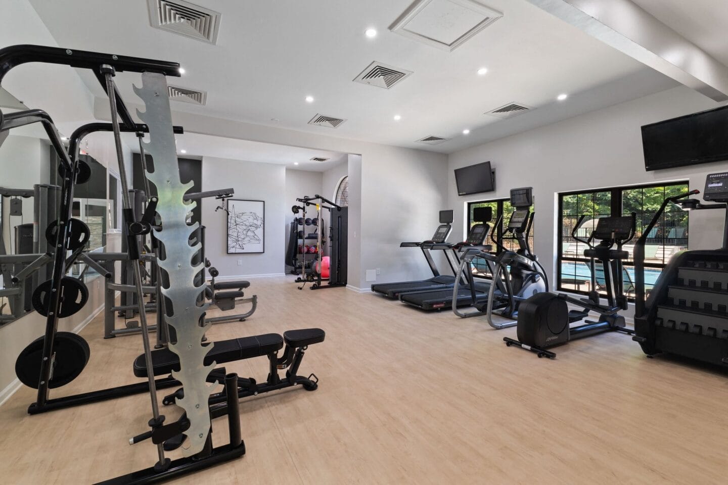 a gym with cardio equipment and a tv on the wall