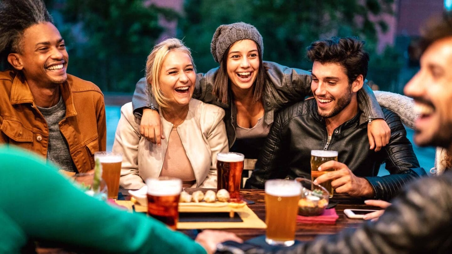 a group of people sitting around a table with beers