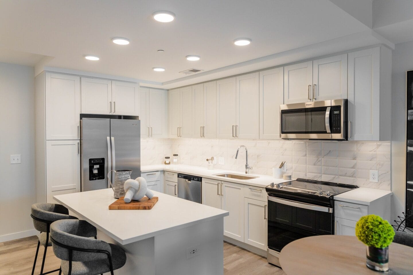 a kitchen with white cabinets and black appliances and a white counter top