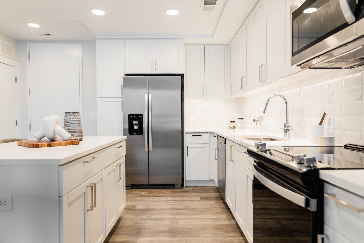 a white kitchen with stainless steel appliances and white cabinets