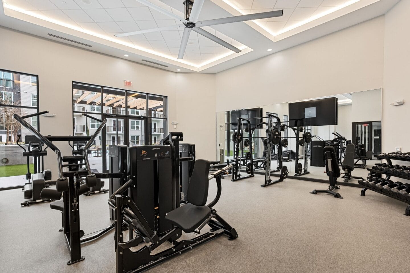 a gym with weights and cardio equipment in a building with large windows