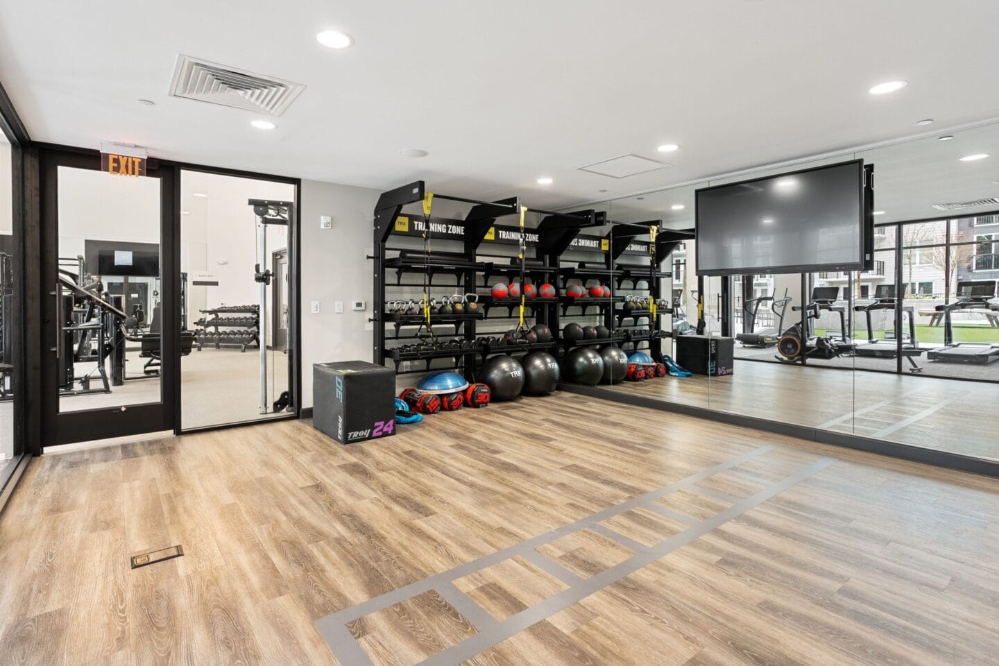 a gym with a wooden floor and a lot of weights on the walls