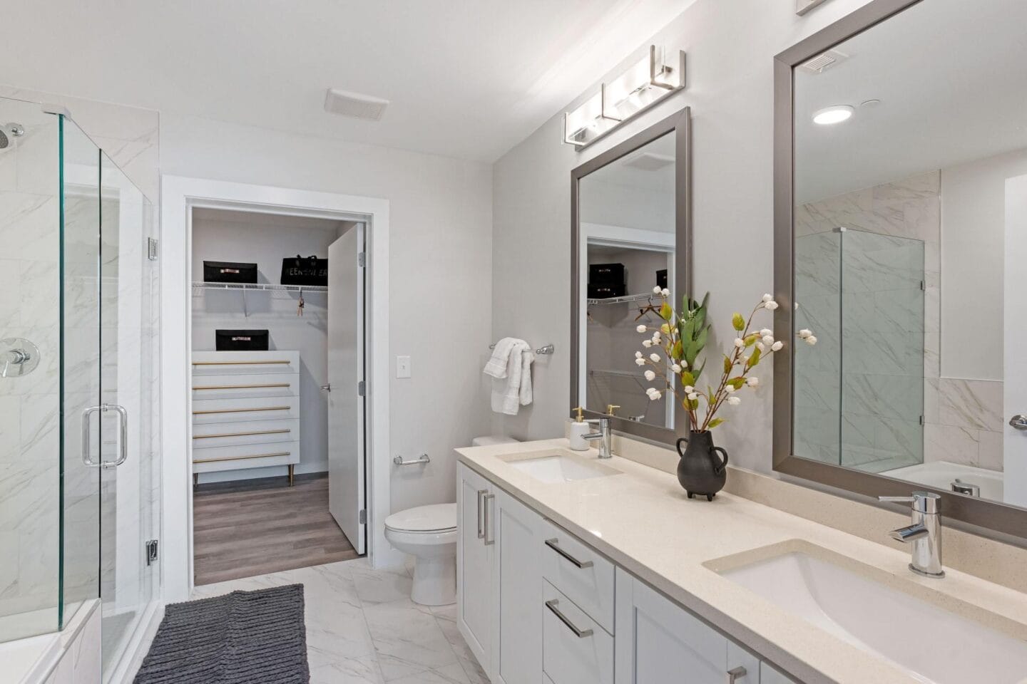 a white bathroom with a large mirror and a shower