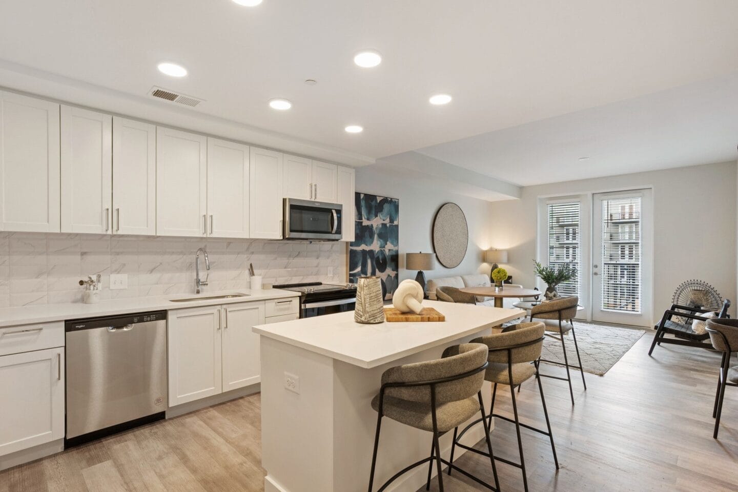 an open kitchen and living room with white cabinets and a table with chairs