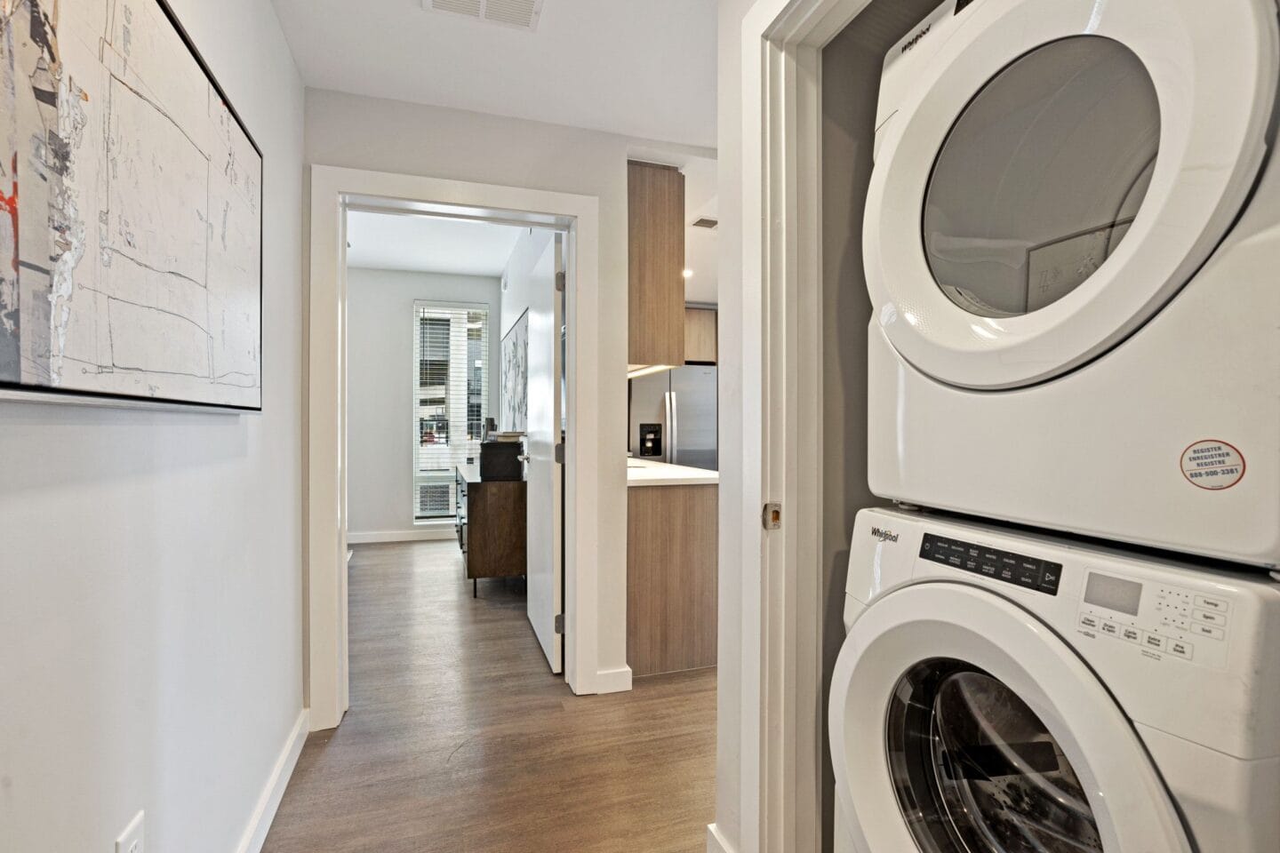 a washer and dryer in a living room with a hallway and a kitchen