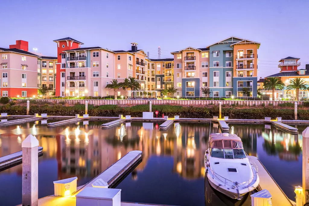 A serene marina at night, featuring boats peacefully docked under a starlit sky, reflecting lights on the water's surface.