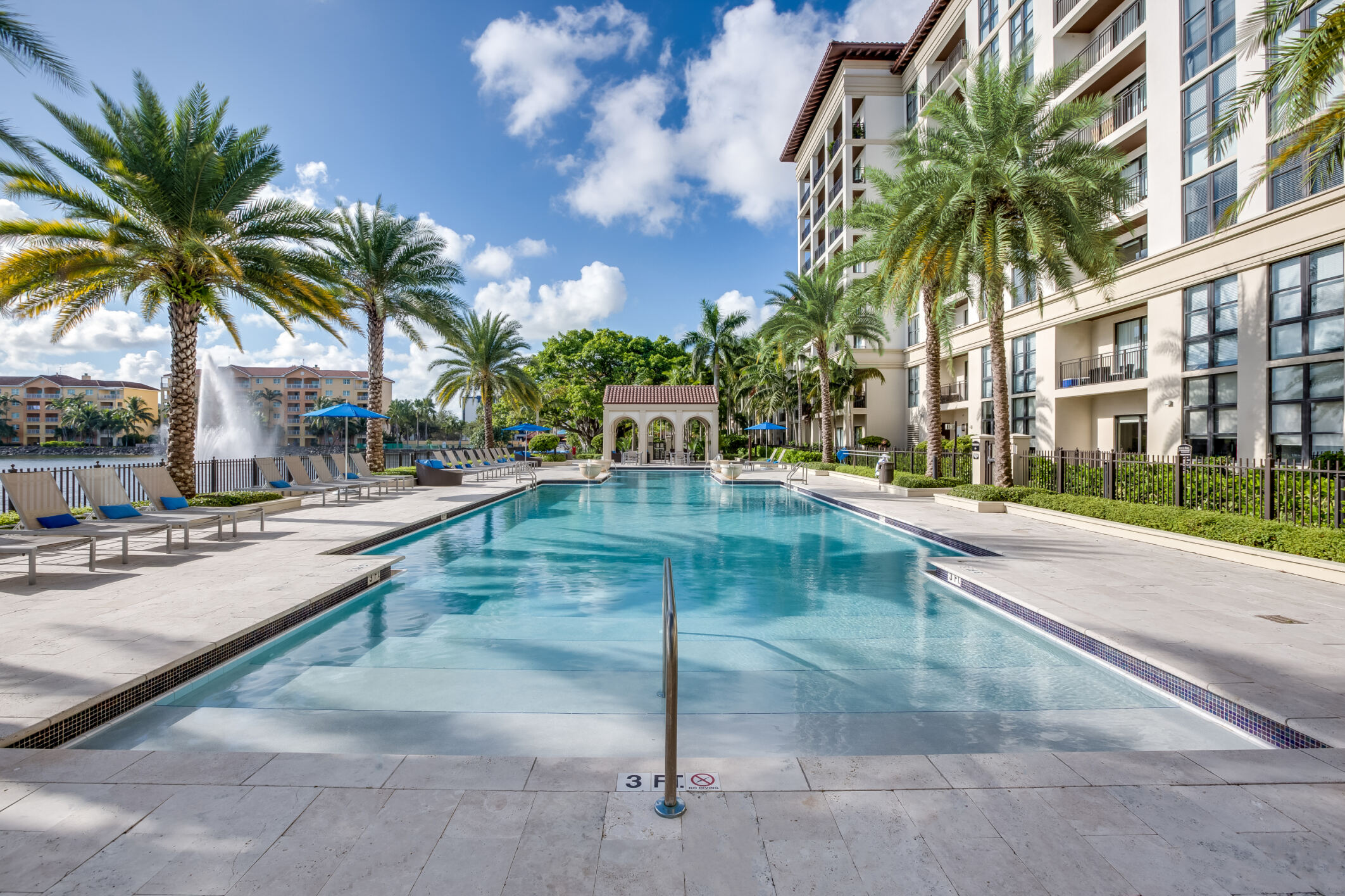 a swimming pool with palm trees and a building