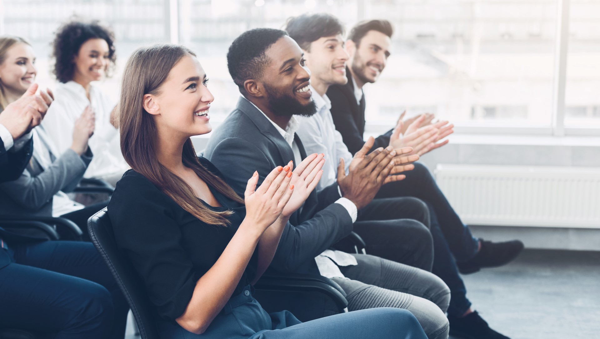 A group of business professionals applauding during a meeting, showcasing teamwork and appreciation for shared ideas.