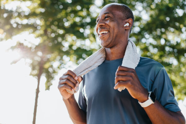 A person with a cheerful expression holding a towel around his neck with both hands.