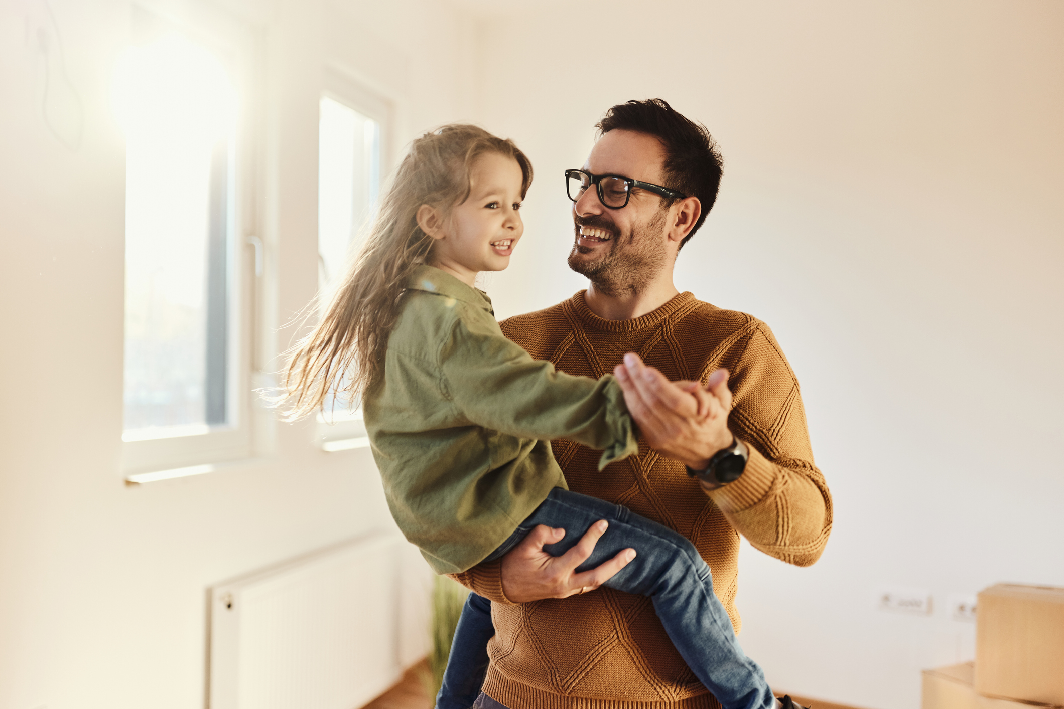 Carefree father and daughter dancing at their new apartment.