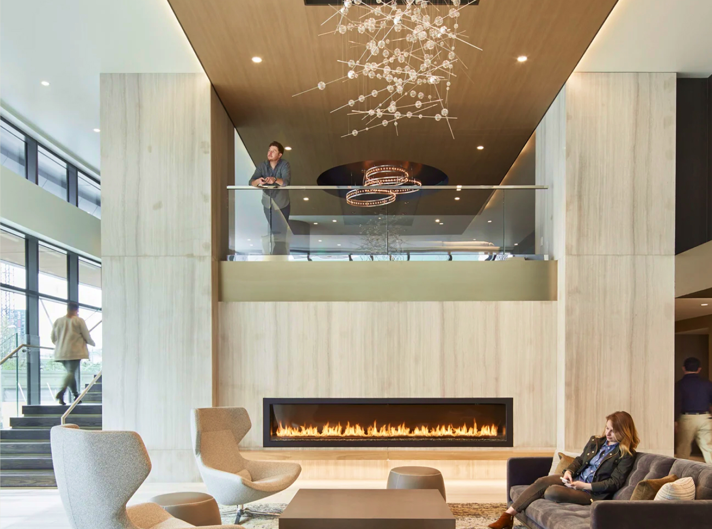 A contemporary lobby featuring a cozy fireplace surrounded by stylish chairs, creating a welcoming atmosphere.