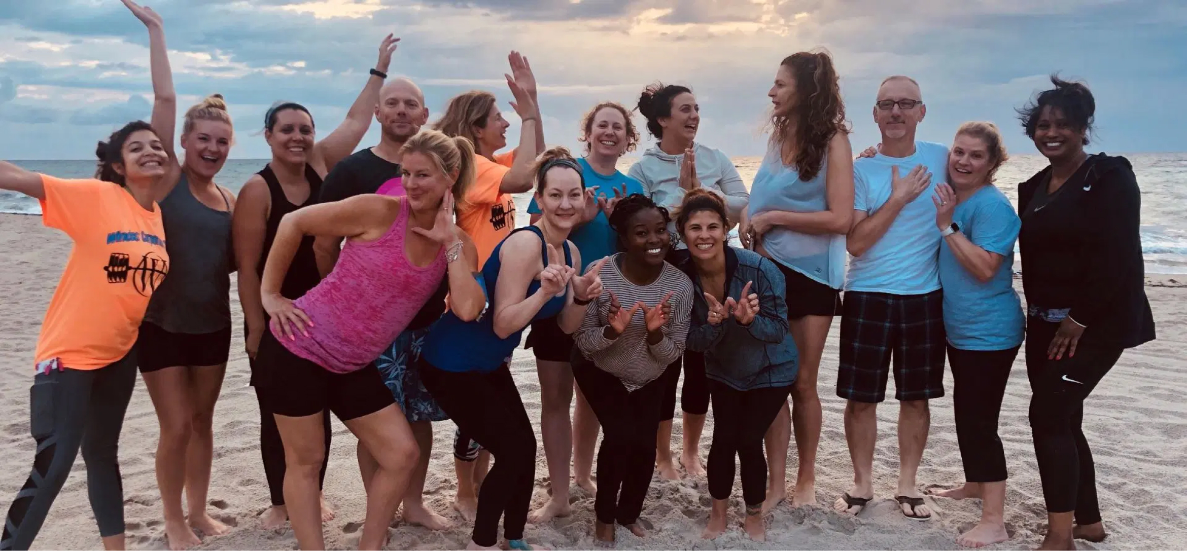 A cheerful group of people stands together on the beach, capturing a joyful moment in a photograph.