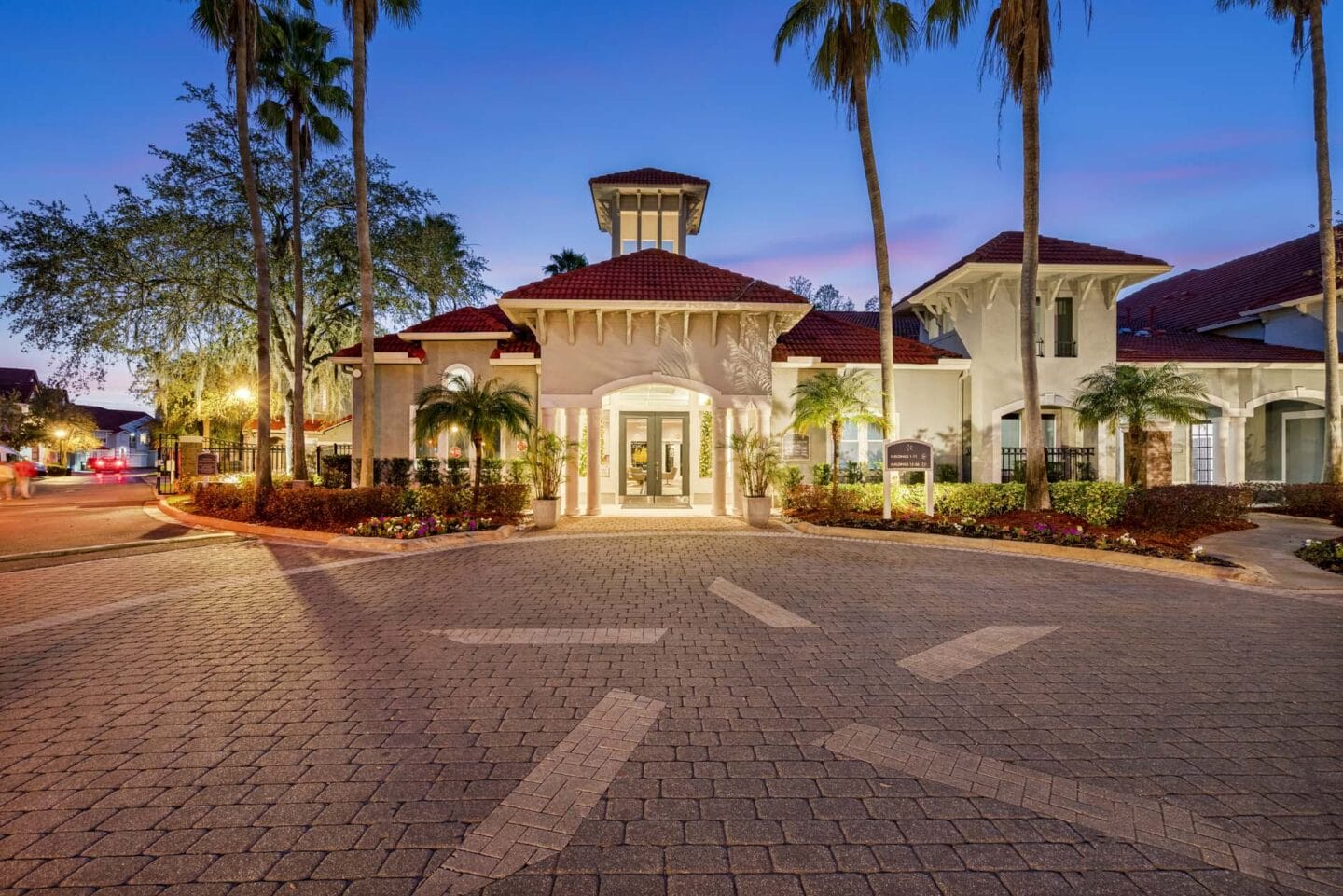 a mansion with a driveway and a building with palm trees