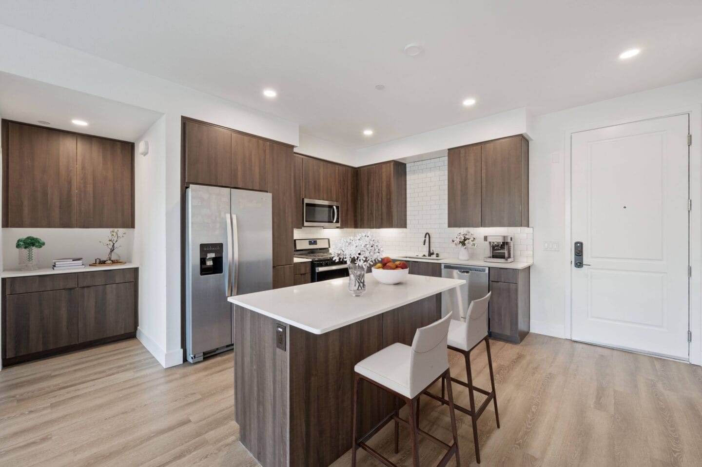 a kitchen with a large island with two white chairs