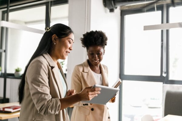 Two women engaging in an active conversation while looking at a tablet