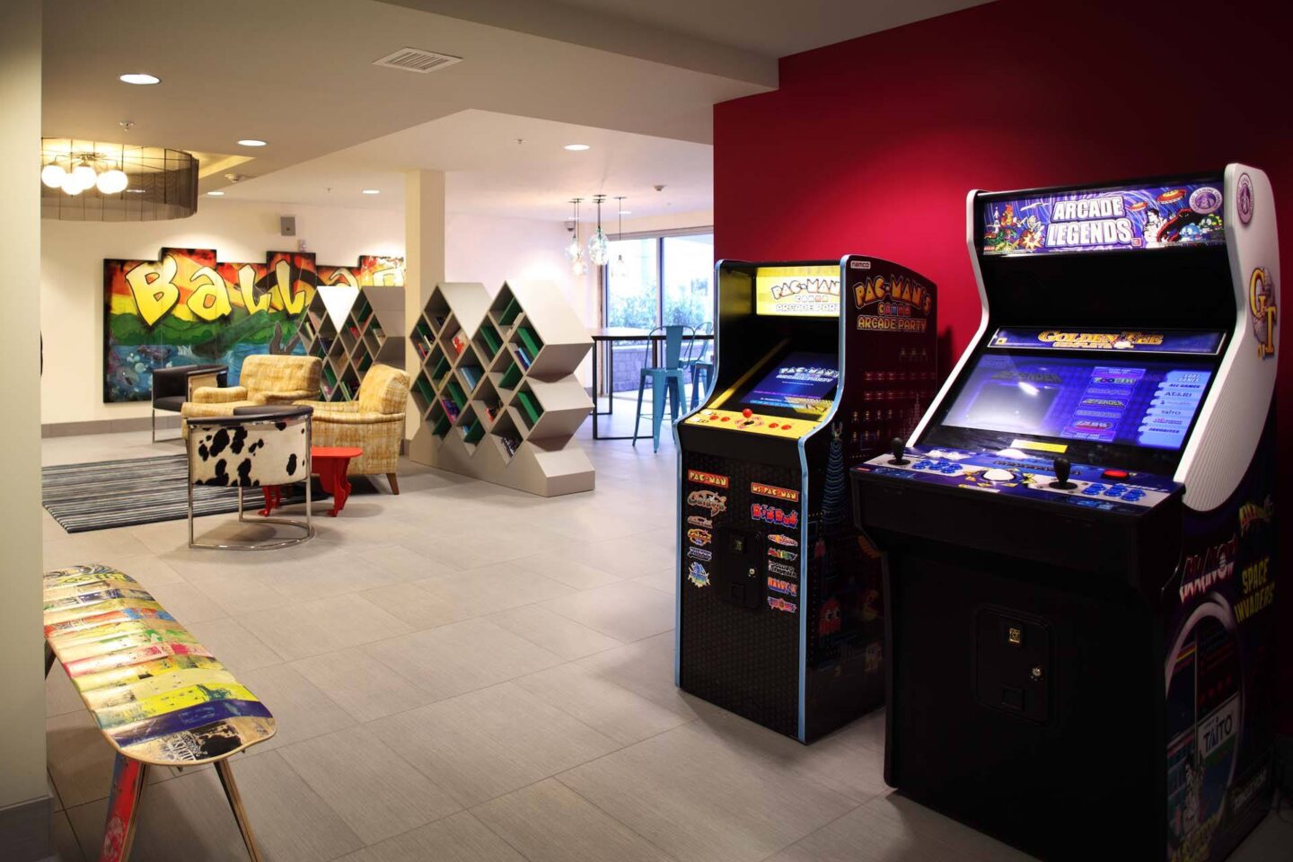 A room with a red wall and a row of arcade games at Windsor Ballard, 5555 14th Ave NW, Seattle, WA