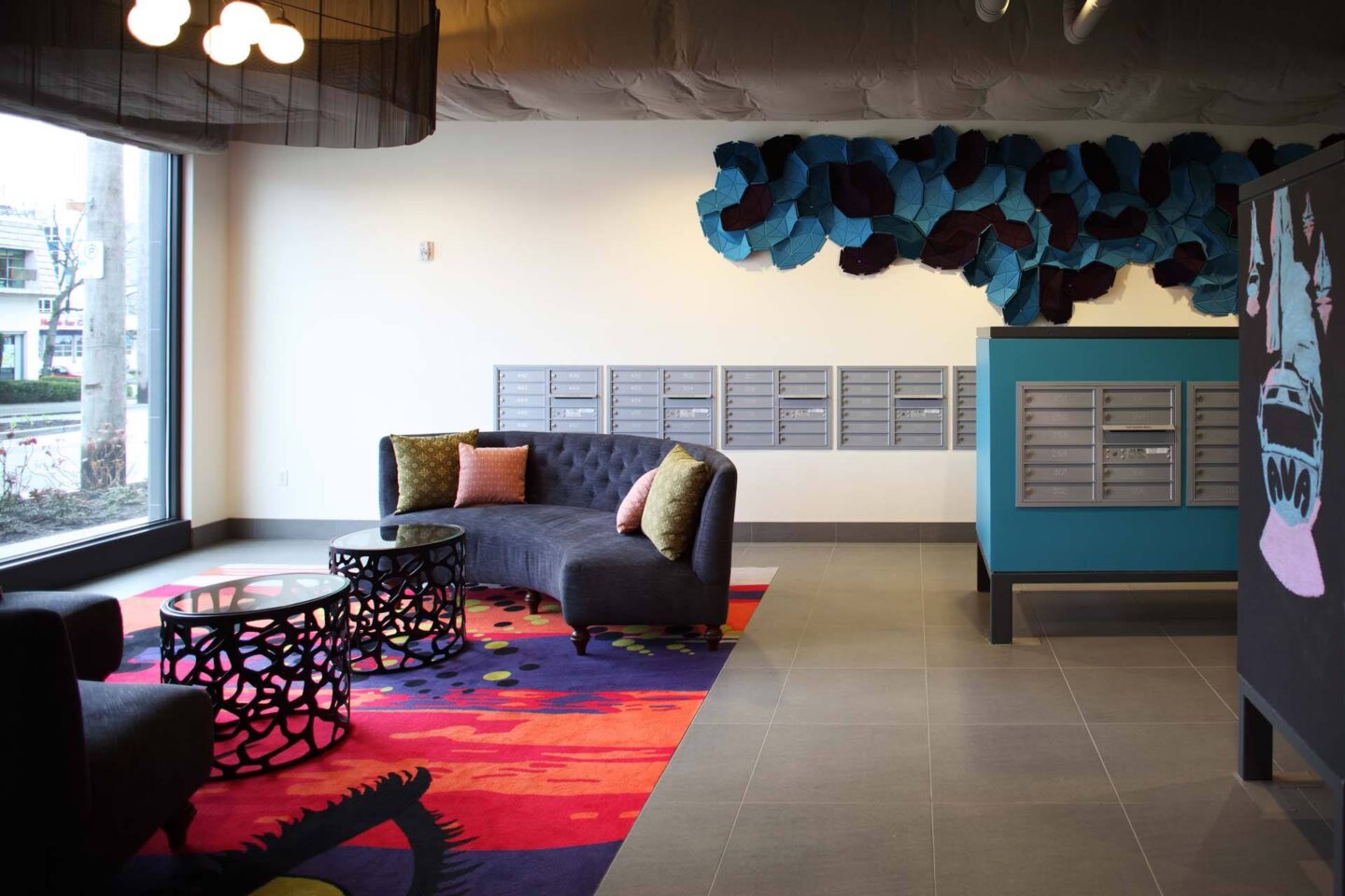 A blue couch with a grey cushion is in the middle of a room with a black table and a red carpet at Windsor Ballard, 5555 14th Ave NW, Seattle, WA