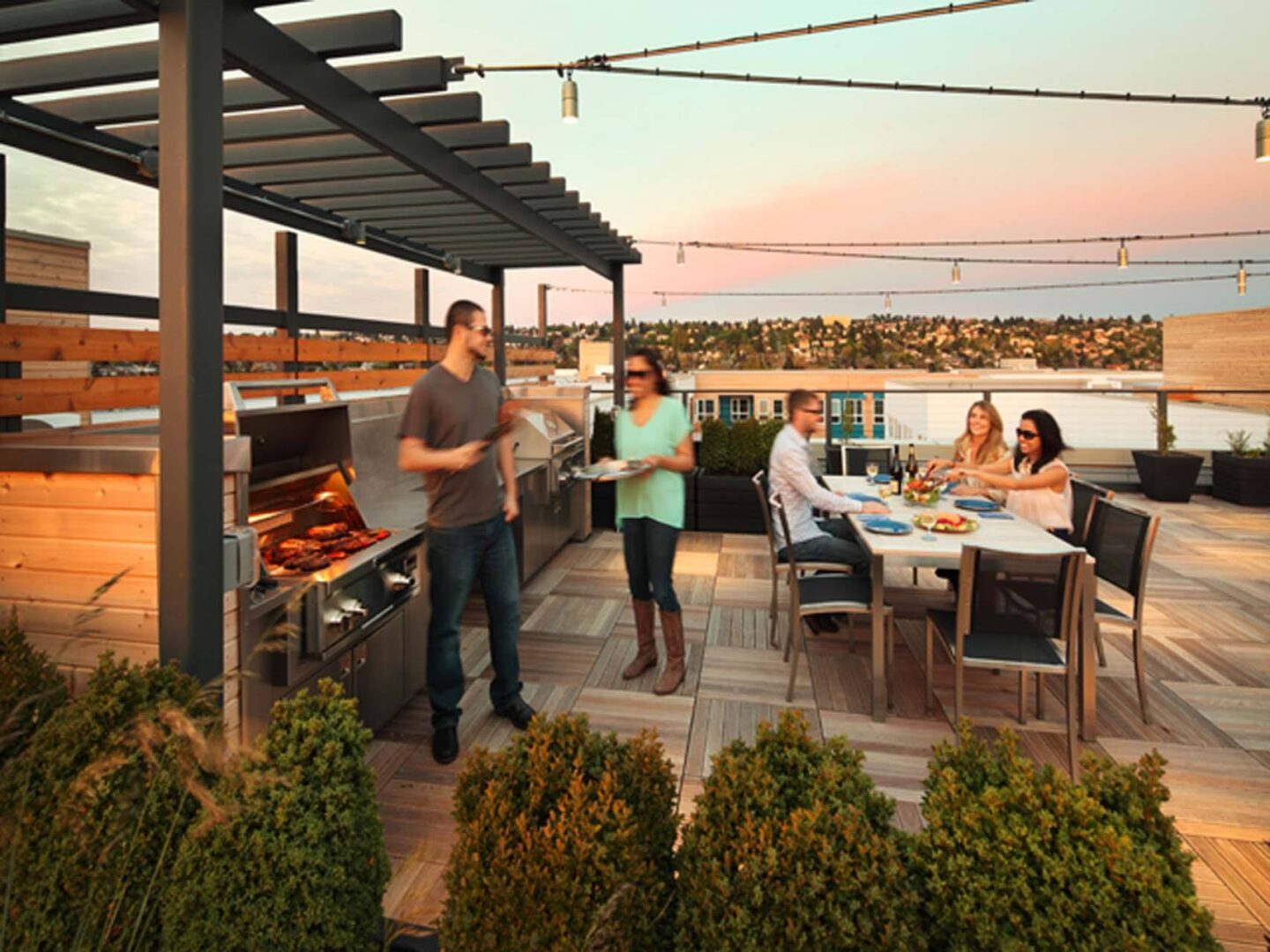 A man is grilling food on a patio with a group of people sitting around a table at Windsor Ballard, 5555 14th Ave NW, Seattle, WA