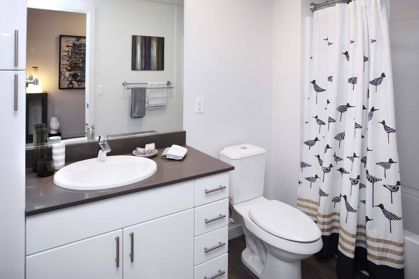 A bathroom with a white toilet, sink, and shower curtain with birds on it at Windsor Ballard, 5555 14th Ave NW, Seattle, WA