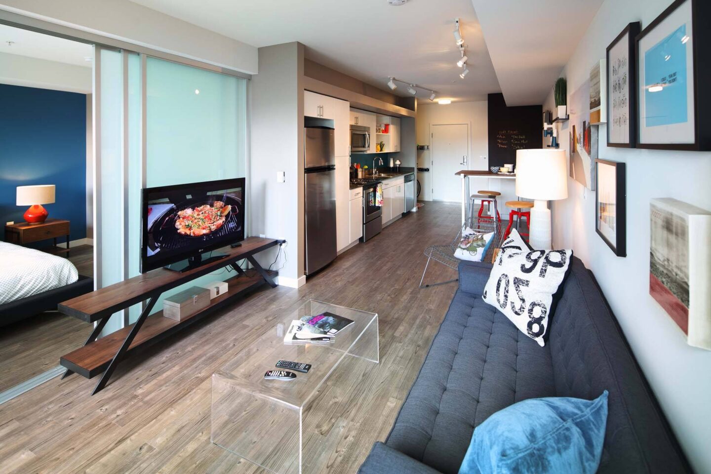 A modern living room with a flat screen TV and a kitchen in the background at Windsor Ballard, 5555 14th Ave NW, Seattle, WA