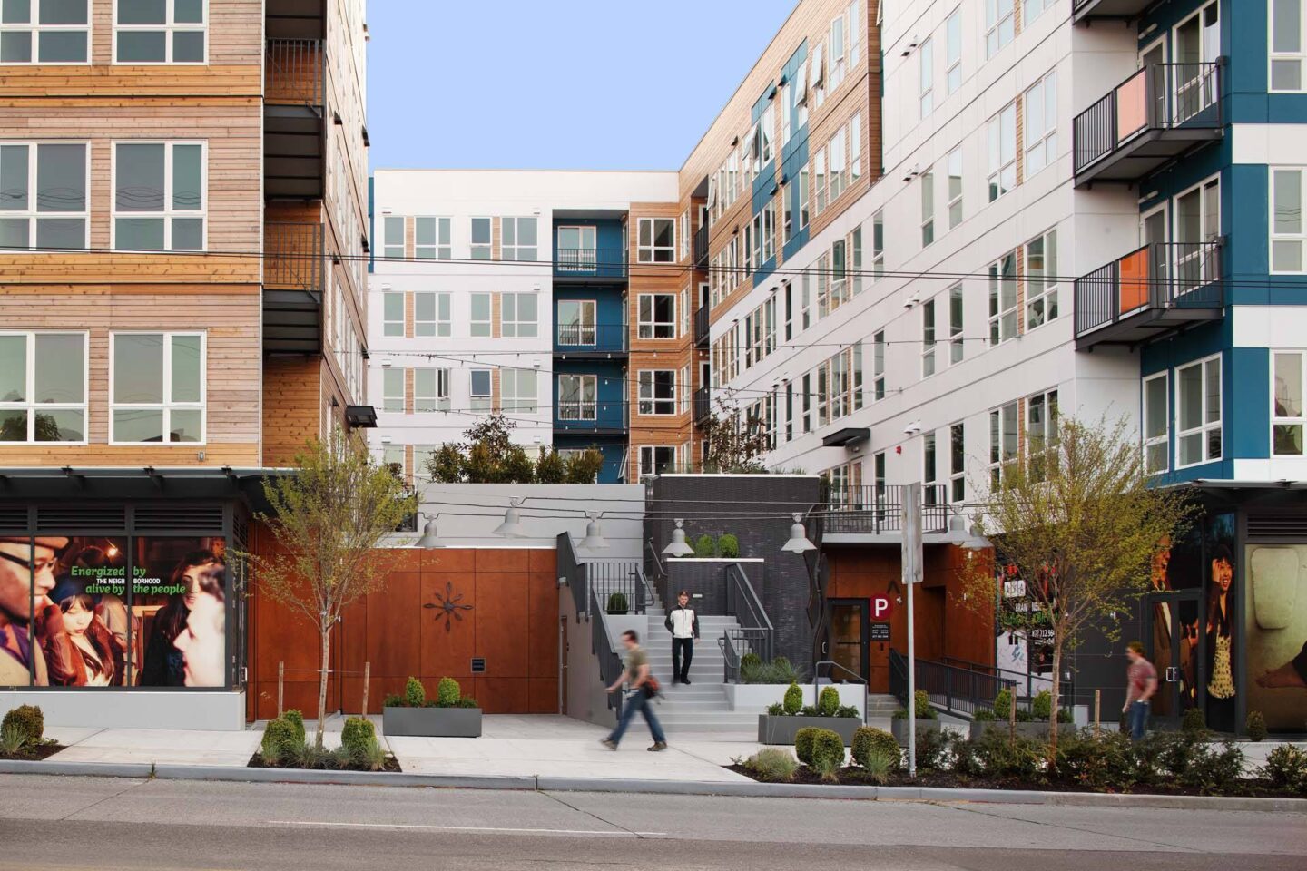 A man is walking on a sidewalk in front of a building.