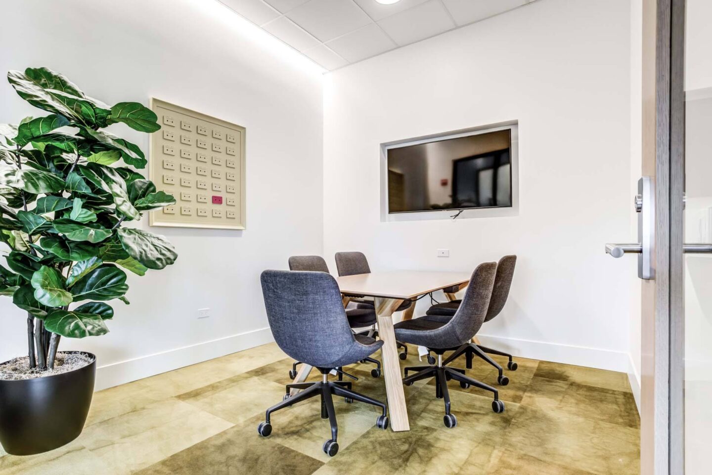 A conference room with a large table, chairs, and a plant at Windsor North + Vine 633 W North Ave, Chicago, IL 60610.