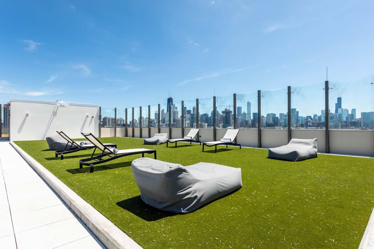 A rooftop patio with white chairs and cushions overlooking a city skyline.