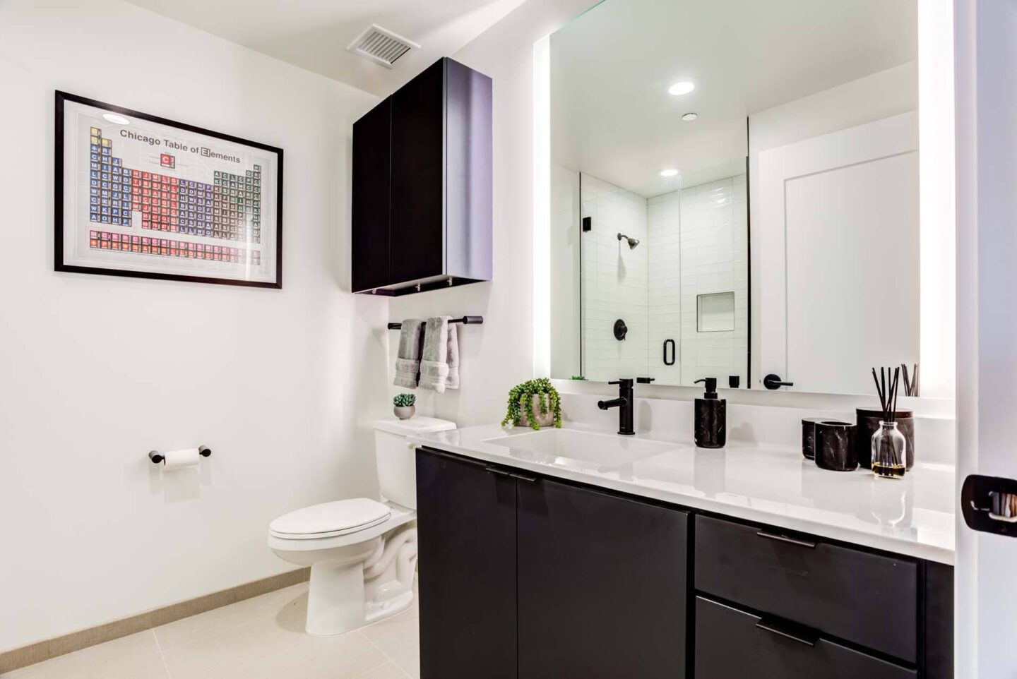 A bathroom with a toilet, sink, and a framed map on the wall at Windsor North + Vine 633 W North Ave, Chicago, IL 60610.