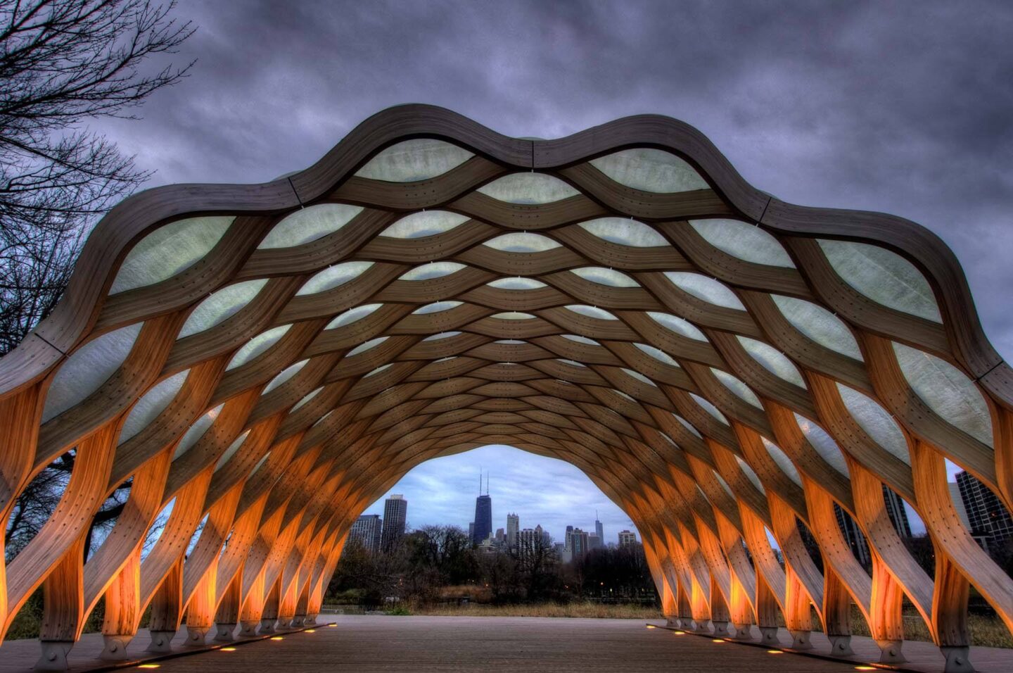 A wooden structure with a unique design is illuminated from within, creating a warm glow against the evening sky in the neighborhood at Windsor North + Vine 633 W North Ave, Chicago, IL 60610.