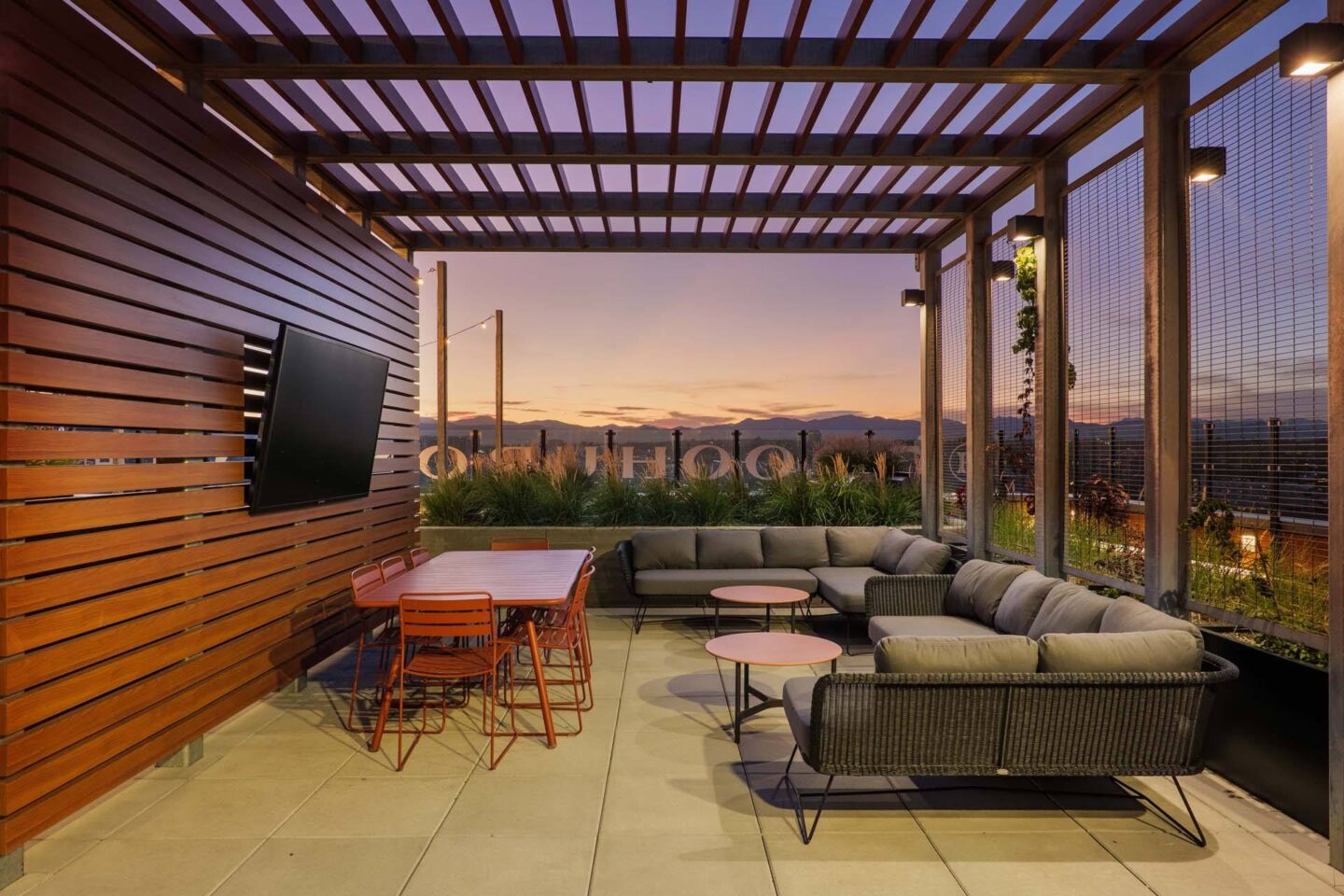 A rooftop lounge offering stunning mountain views, featuring a TV, a stylish table, and a comfortable couch at Windsor 3000 Huron, 3000. N. Huron Street, Denver, CO 80202.