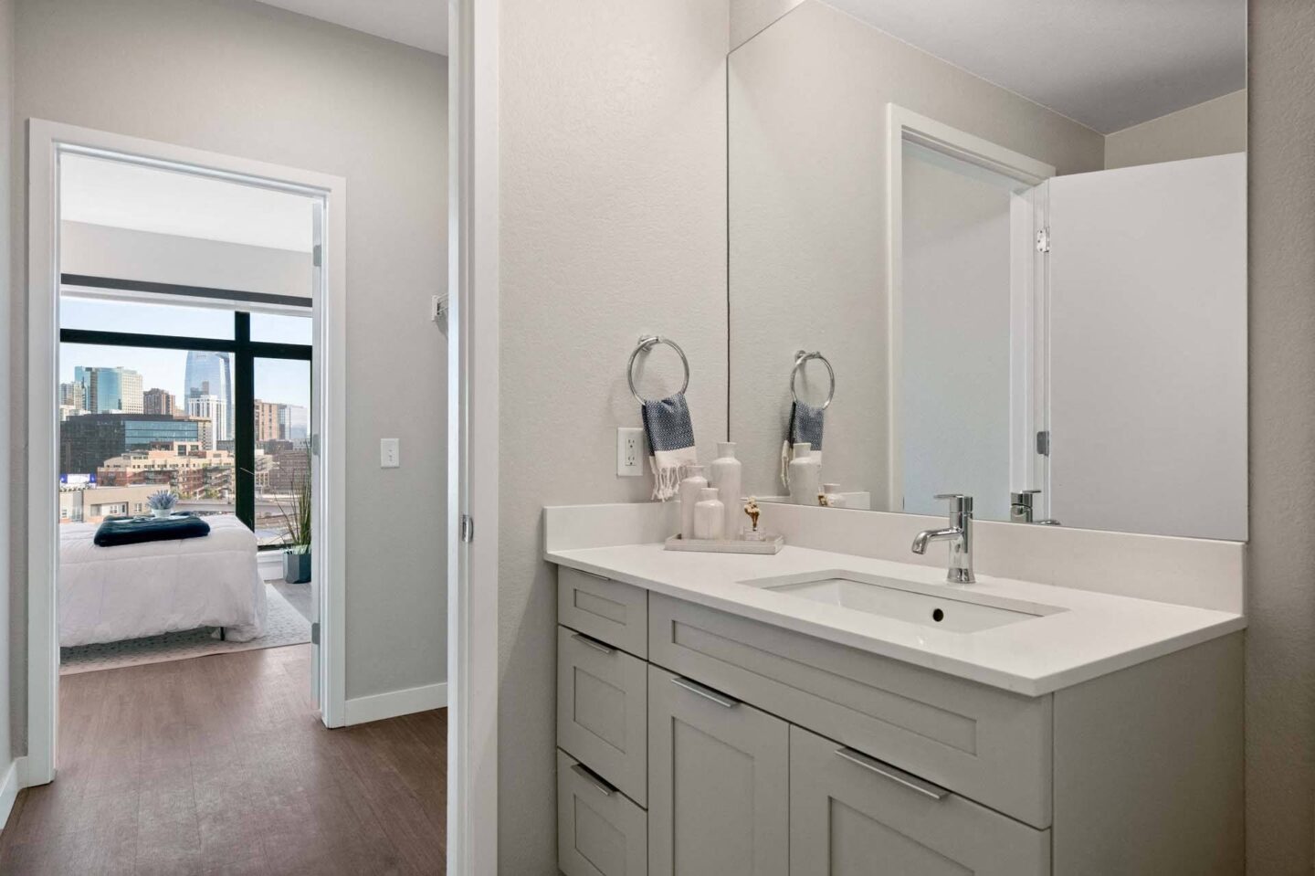 A bathroom with a large mirror and a bedroom with a bed and a large city view at Windsor 3000 Huron, 3000. N. Huron Street, Denver, CO 80202.