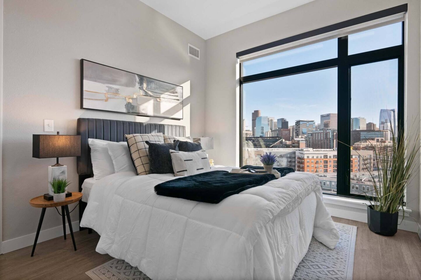 A bedroom with a large bed and a city view through the window at Windsor 3000 Huron, 3000. N. Huron Street, Denver, CO 80202.